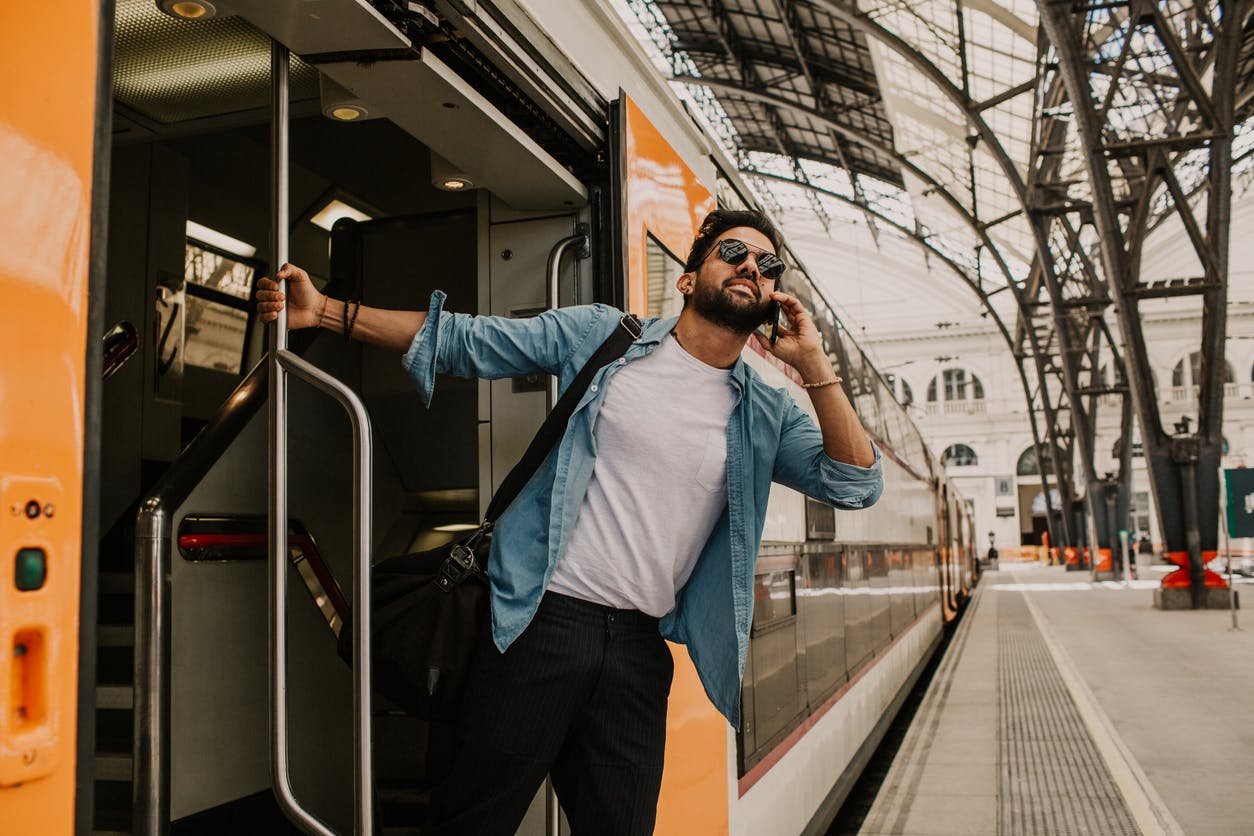 Mies matkustamassa junalla puhelin korvallaan
