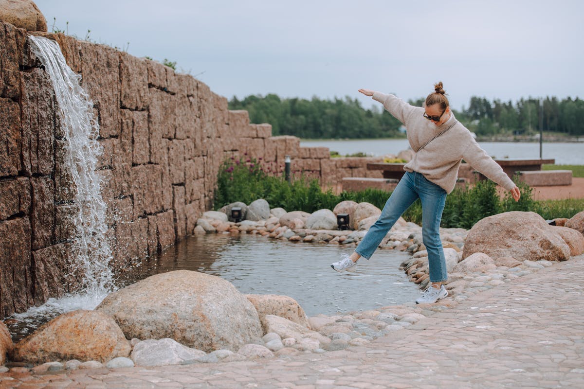Nainen tasapainoilee kivien päällä Oolanninpuistossa.